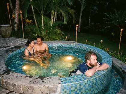 Guests in a round mosaic hot pool at a Bali wellness club in the evening